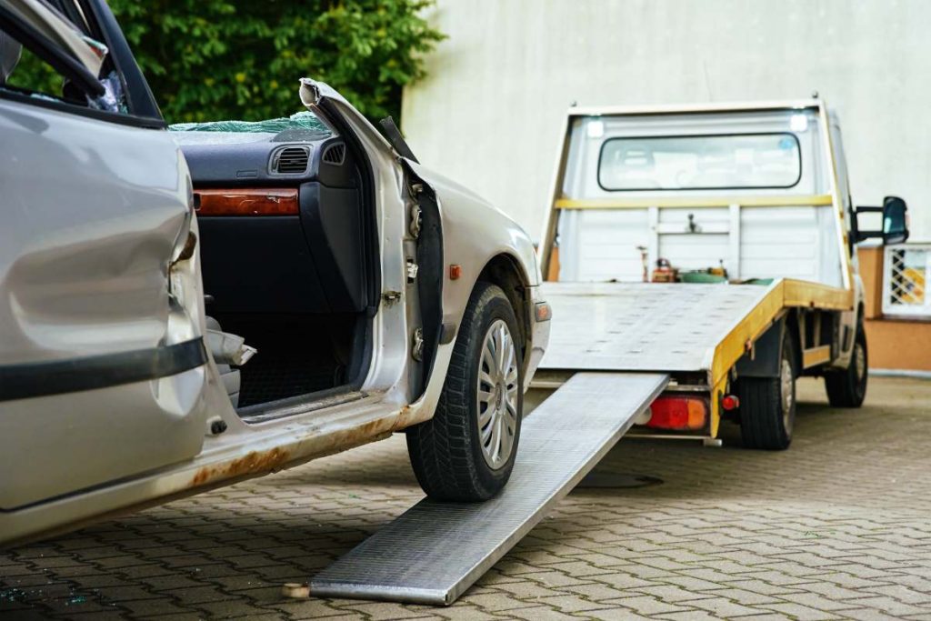 Wrecked car loading on tow truck after crash traffic accident, Concept of dangerous driving after drinking alcohol, Roadside assistance concept