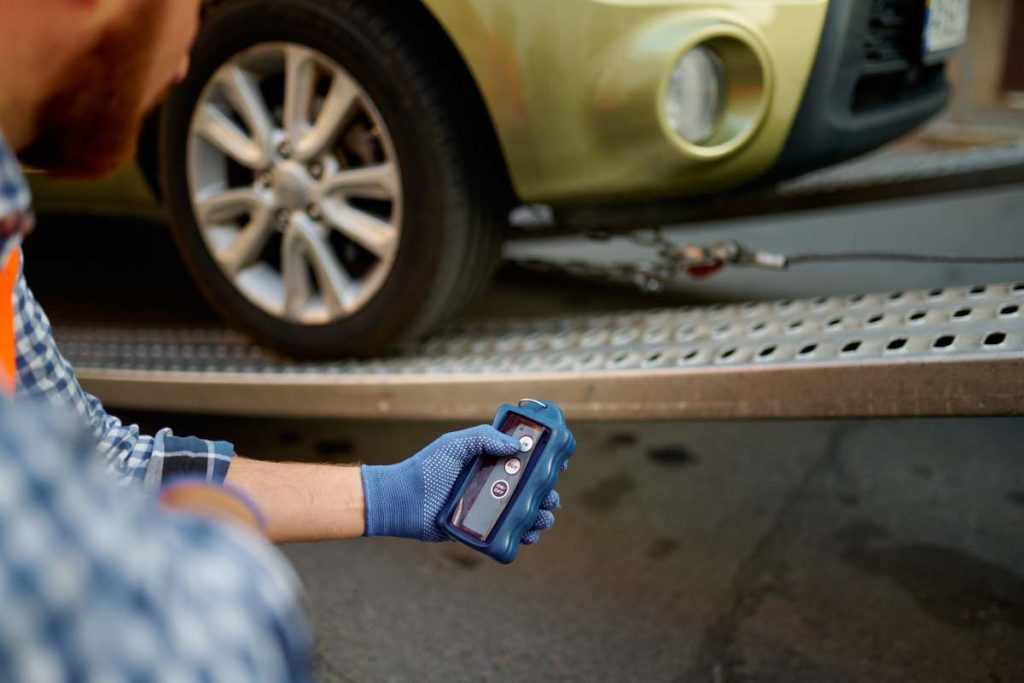 Closeup view on male road worker wearing uniform monitoring car loading process on evacuator platform