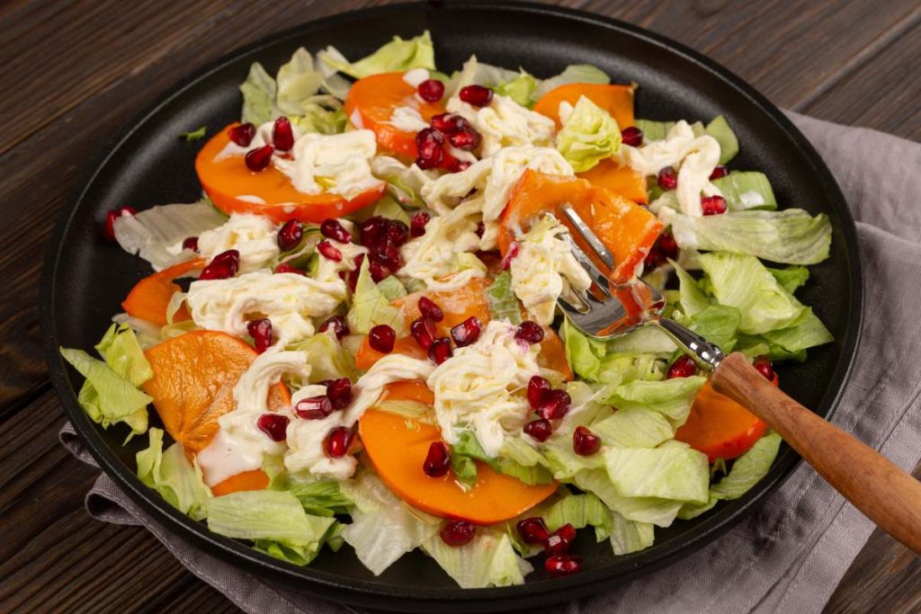 Salad with persimmon, strachatella cream cheese and pomegranate, open space