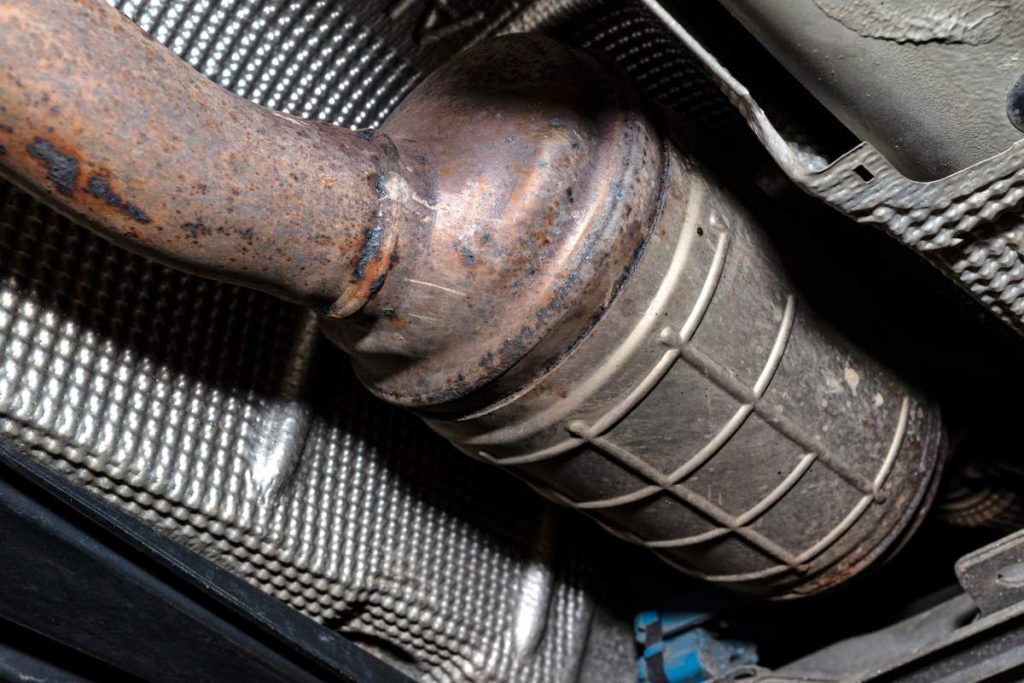 A diesel particulate filter in the exhaust system in a car on a lift in a car workshop, seen from below.