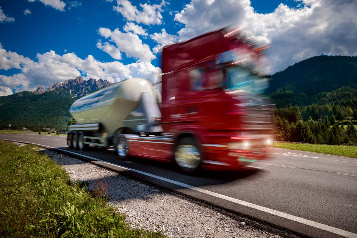 Fuel truck rushes down the highway in the background the Alps. Truck Car in motion blur.