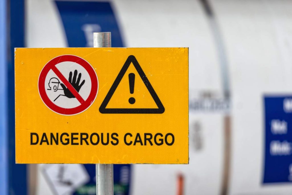 Signs warn of job security. Sign 'dangerous cargo'.