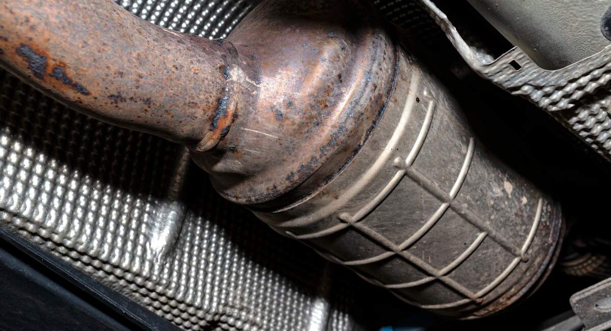 A diesel particulate filter in the exhaust system in a car on a lift in a car workshop, seen from below.