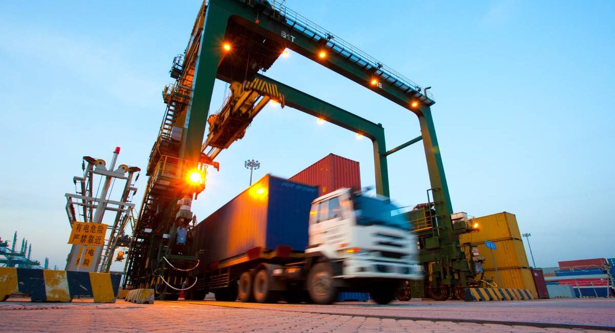 What Is Freight Forwarding? Everything You Need to Know Blurred motion of truck with cargo containers and cranes in a shipping port