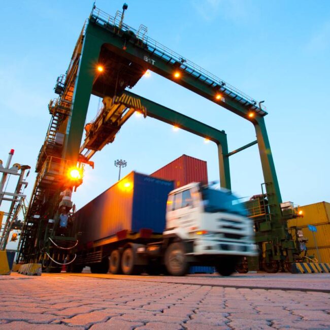 What Is Freight Forwarding? Everything You Need to Know Blurred motion of truck with cargo containers and cranes in a shipping port