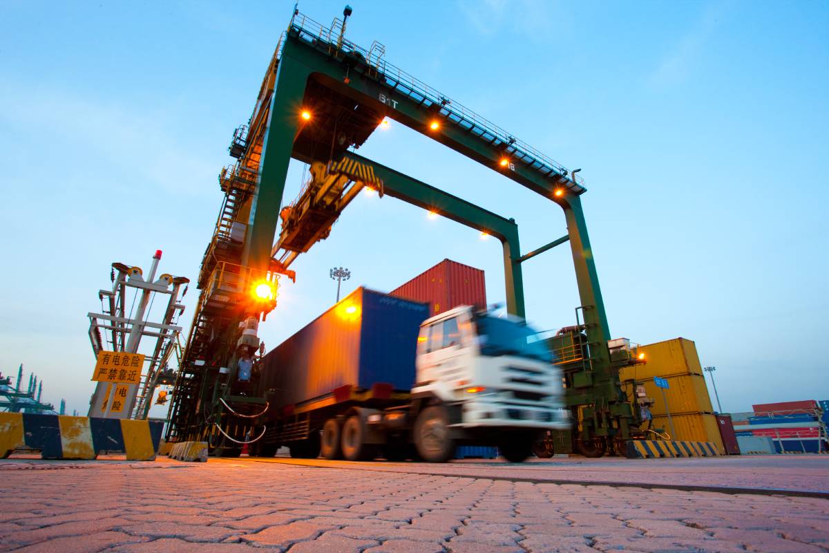 What Is Freight Forwarding? Everything You Need to Know Blurred motion of truck with cargo containers and cranes in a shipping port