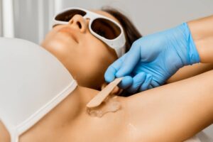 Close up beautician applies gel on armpit for laser epilation/hair removal.