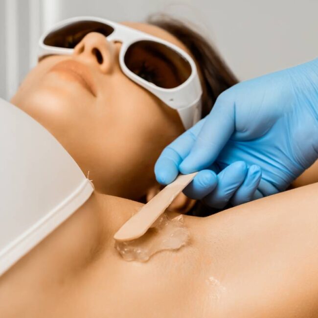 Close up beautician applies gel on armpit for laser epilation/hair removal.