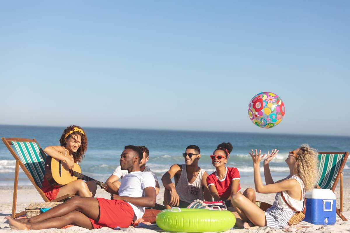 Front view of group of happy diverse friends having fun together on the beach