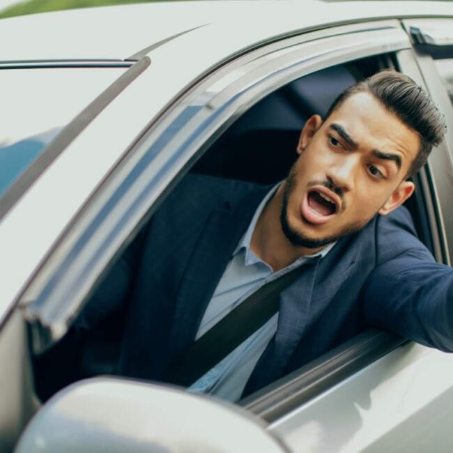 Furious middle-eastern businessman driving car, fighting with other drivers on road, emotional arab man getting late for business meeting or flight, stuck in traffic, yelling and gesturing