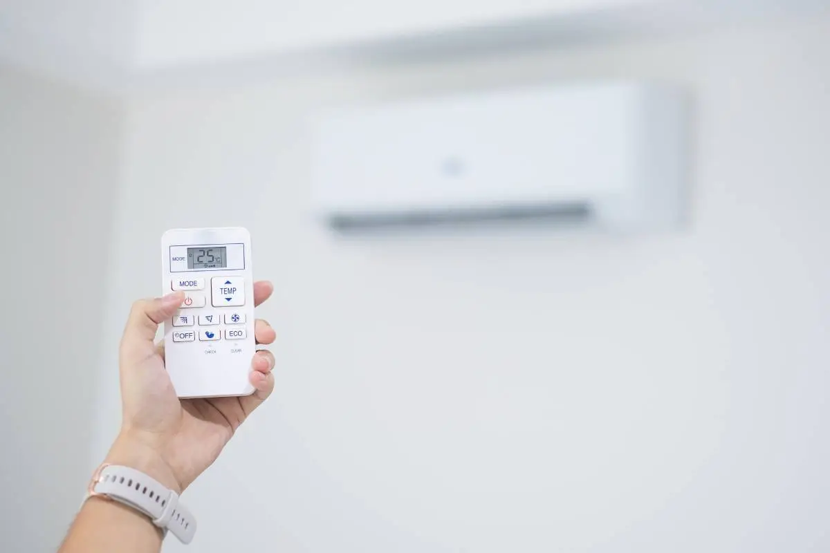 hand using remote controller for adjust Air conditioner inside the room at home