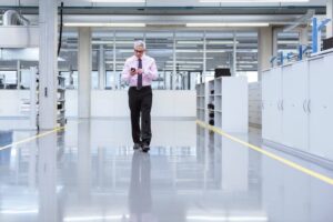 Manager on shop floor of a factory using smart phone