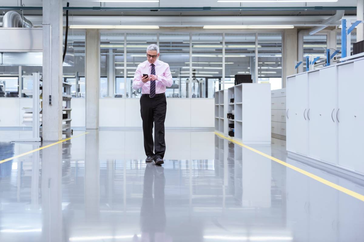 Manager on shop floor of a factory using smart phone