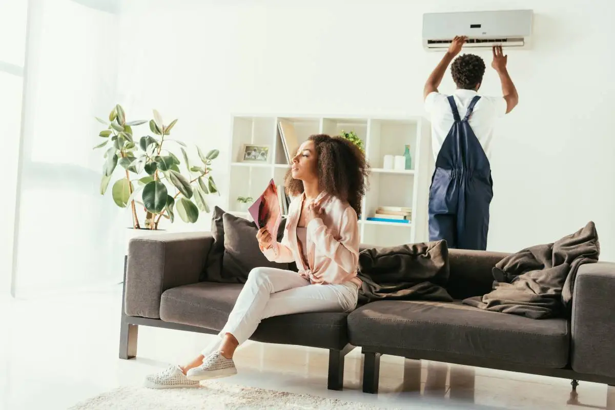 pretty african american woman sitting on couch and waving with magazine, while african american