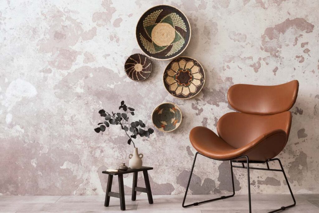 The stylish ethnic composition at living room interior with design brown armchair, colorful baskets, coffee table and elegant personal accessories. Grey concrete wall. Cozy apartment. Home decor.