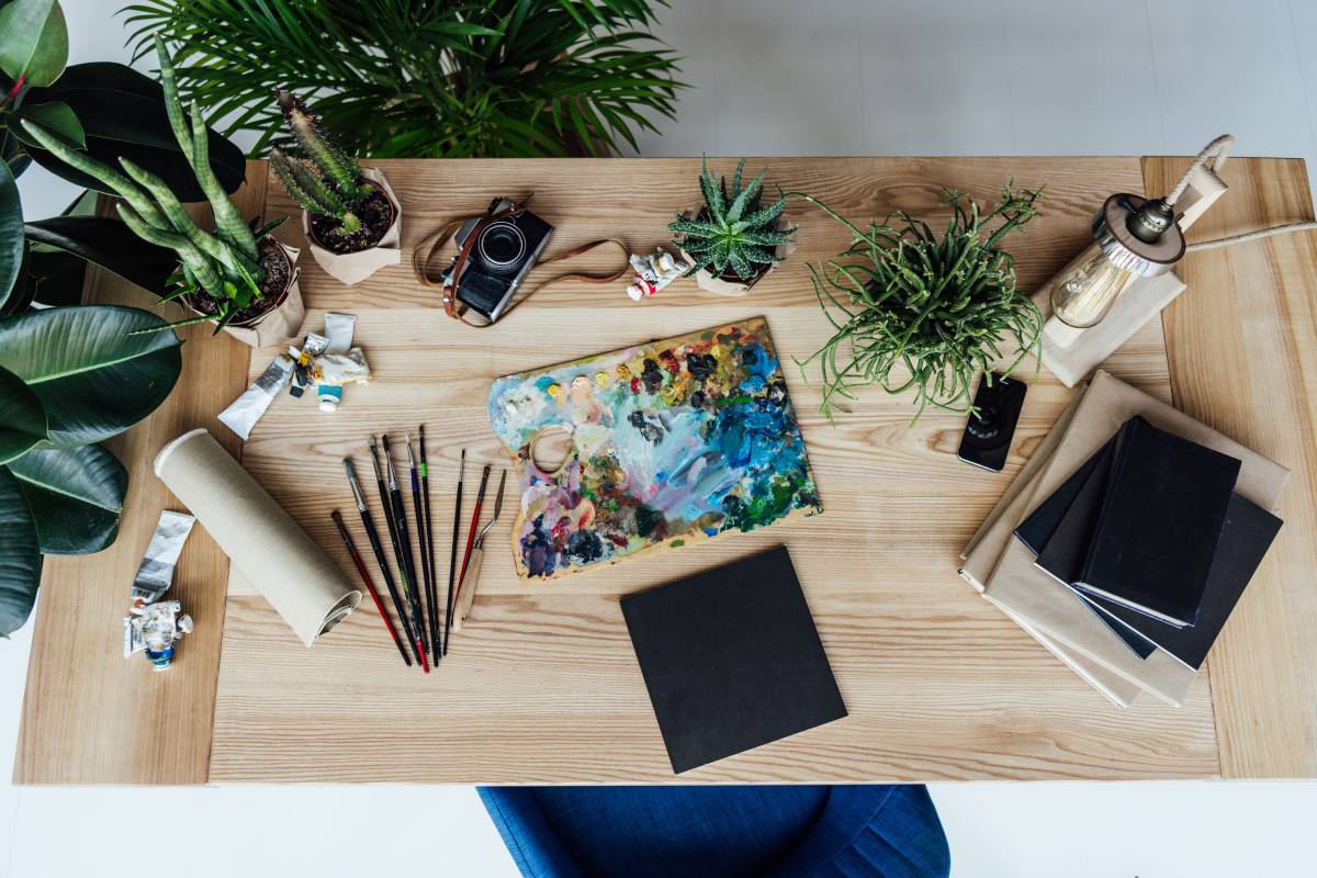 Top view of painter workplace with drawing equipment, potted plants and stack of books